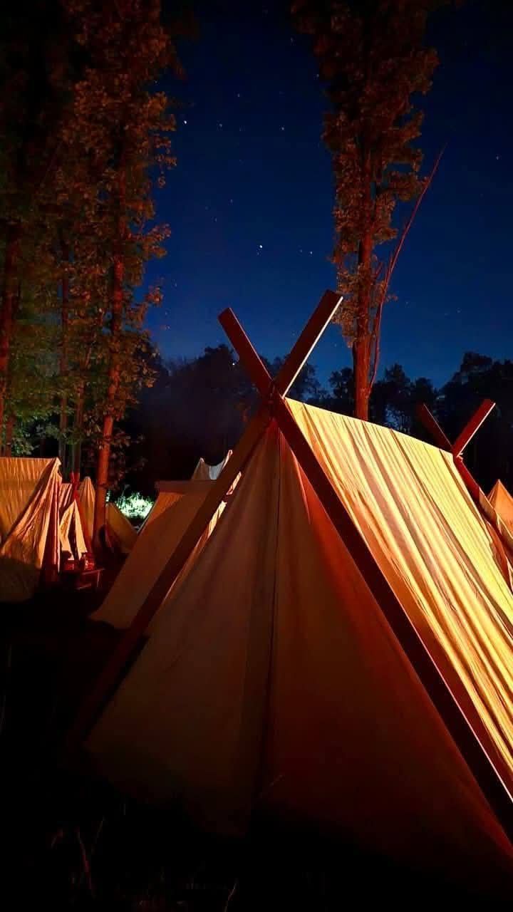 Canvas tents glowing at night under a starry sky